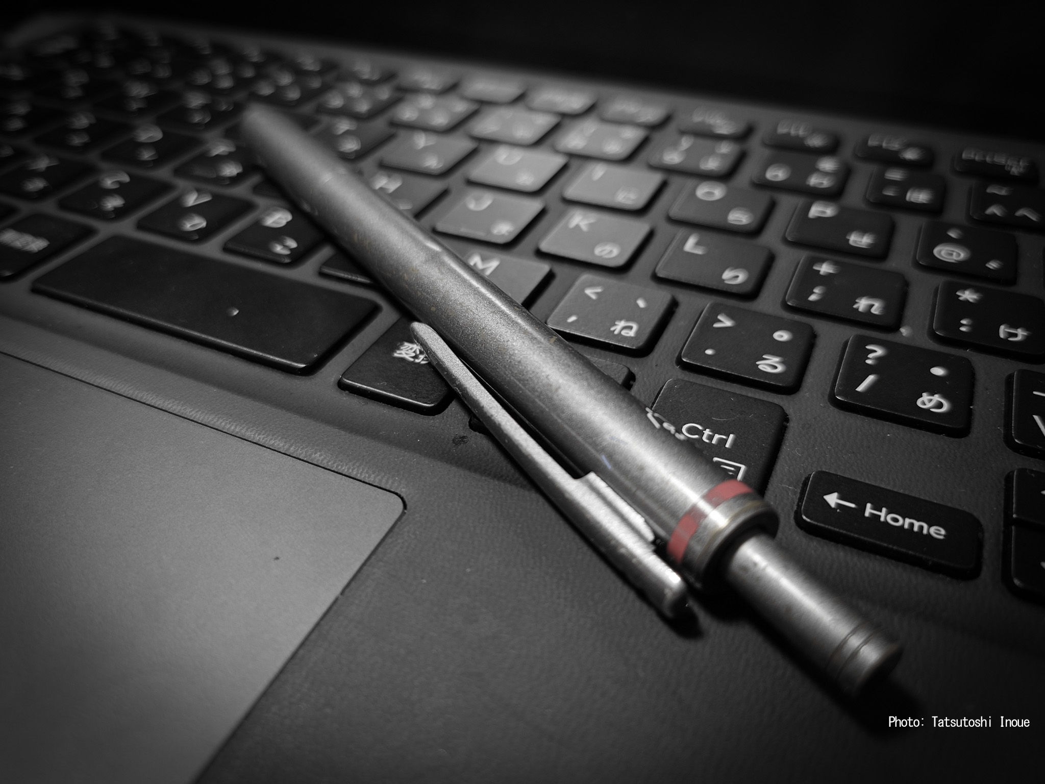 ノートパソコンのキーボード上に置かれたロットリングの振り子式ペン / A Rotring pendulum-style pen placed on a laptop keyboard